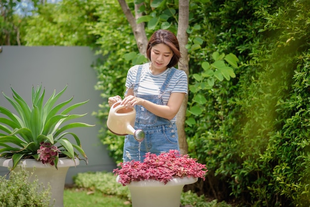 Una donna asiatica sta innaffiando le piante nel giardino