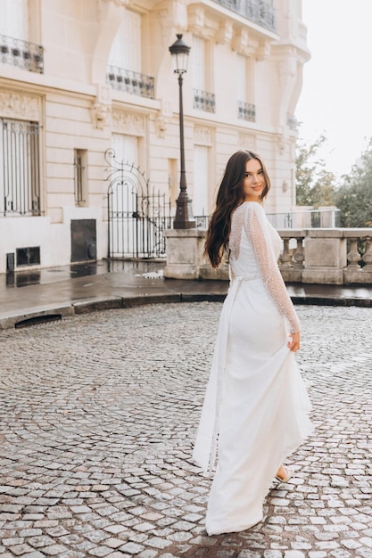 Una donna attraente in abito bianco cammina per le strade di Parigi