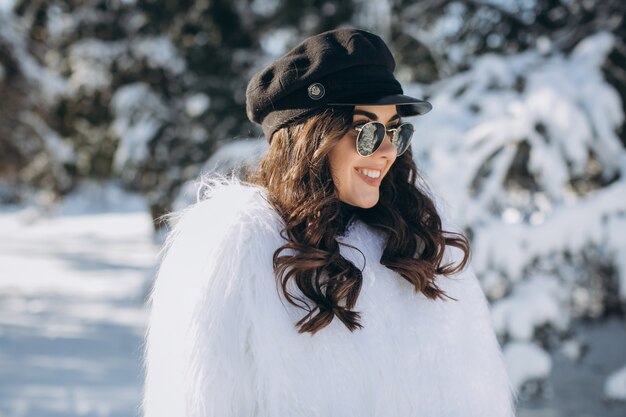 Una donna bella, elegante, alla moda in un cappotto di pelliccia, cappello e occhiali