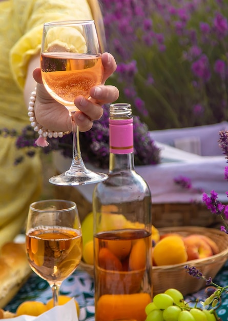 Una donna beve vino in un campo di lavanda Messa a fuoco selettiva