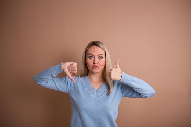 Una donna bionda con un maglione blu mostra le sue mani male e bene su uno sfondo beige con un posto per il testo