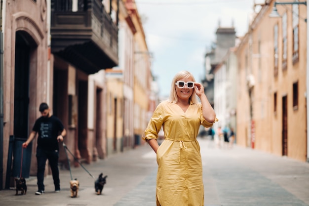 Una donna bionda in un abito estivo giallo si trova sulla strada del centro storico di La Laguna, sull'isola di Tenerife, Spagna, Isole Canarie.