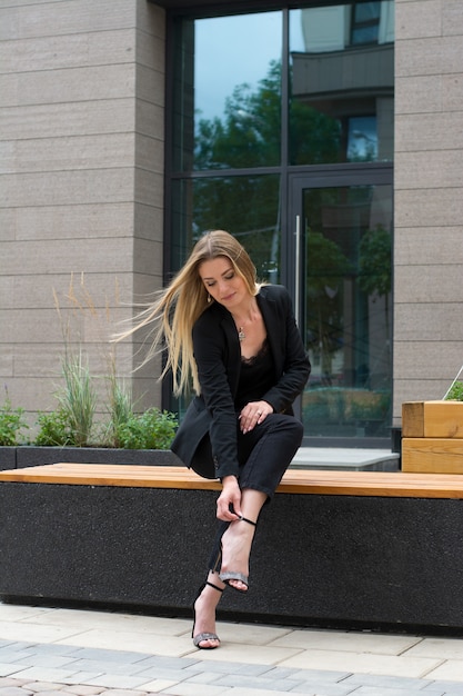 Una donna bionda in un tailleur nero in city.businesswoman in una passeggiata.