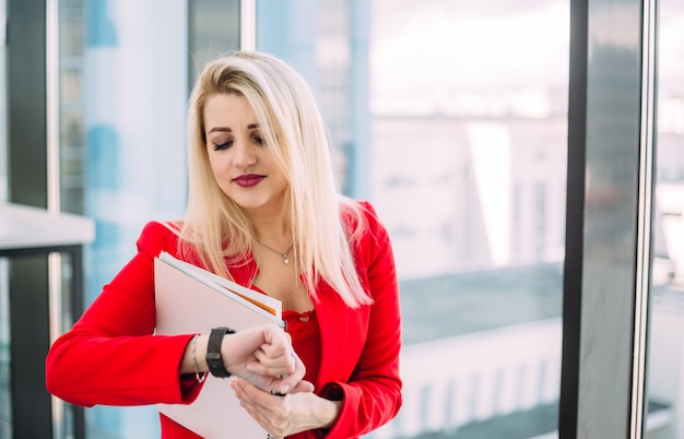 Una donna bionda vestita di rosso che guarda sul suo orologio