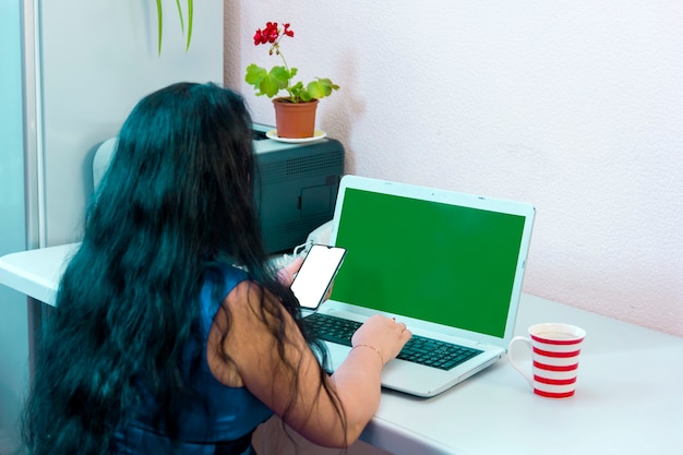 Una donna bruna con le spalle alla telecamera fa acquisti su Internet pagando con una carta di credito online green screen. Foto orizzontale