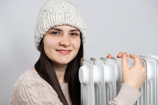 Una donna bruna con un cappello abbraccia una stufa ad olio