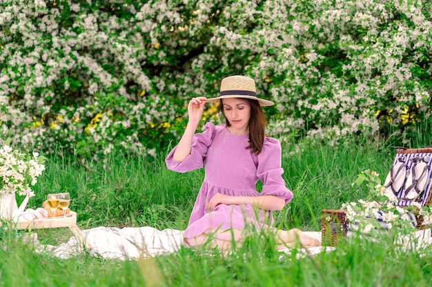 Una donna bruna con un vestito viola posa a un picnic nel parco in primavera