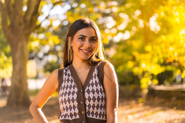 Una donna bruna in autunno al tramonto in un parco naturale cittadino sorridente e divertirsi