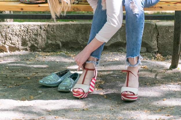 Una donna cambia le scarpe su una panchina nel parco