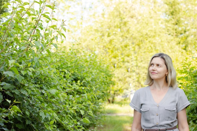 Una donna cammina attraverso il parco e guarda sognante Il trucco modesto sembra naturale