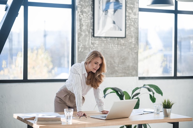Una donna carina ed elegante in ufficio che lavora al computer portatile