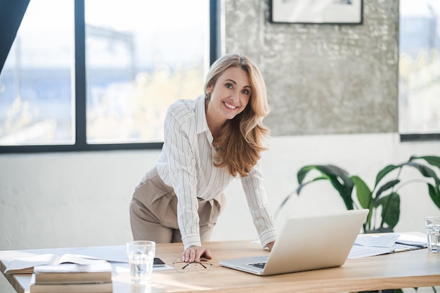 Una donna carina ed elegante in ufficio che lavora al computer portatile