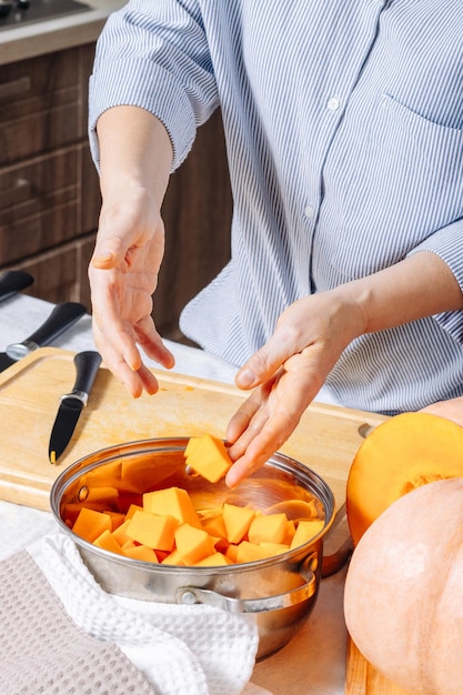 Una donna caucasica anziana che mette pezzi di zucca tagliati in una ciotola