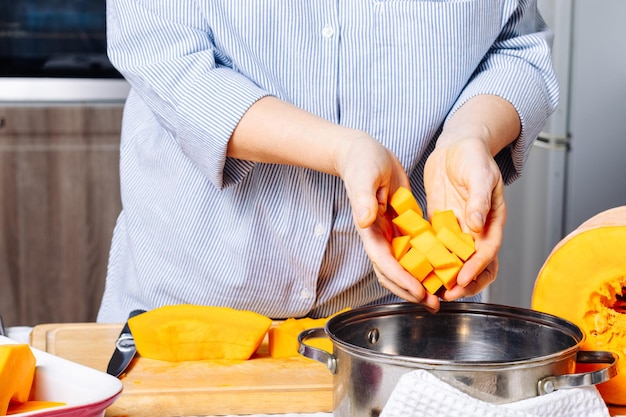 Una donna caucasica anziana che tiene tra le mani pezzi di zucca matura