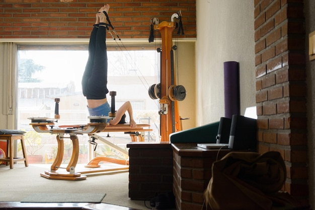 Una donna caucasica nel soggiorno del suo appartamento allena la sua energia e il suo equilibrio con una macchina ginnica