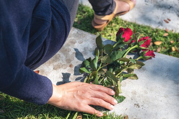 Una donna che afferra e tiene in mano le rose rosse fiorisce a terra mentre è seduto all'aria aperta