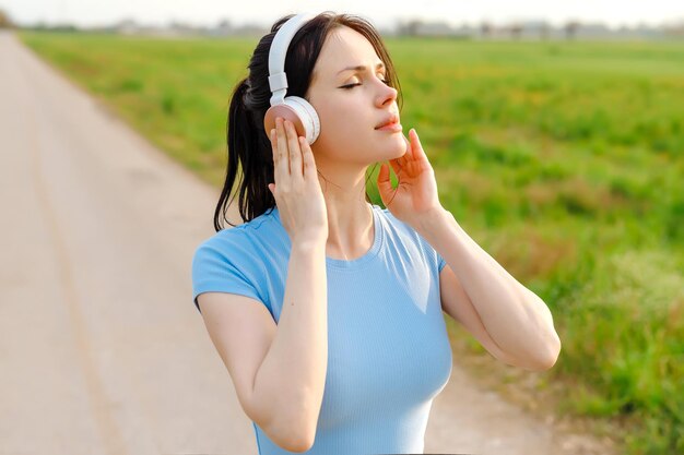 Una donna che ascolta la musica in cuffia chiudendo gli occhi come circondata dalla naturaprofondo relax che abbraccia il piacere del momento