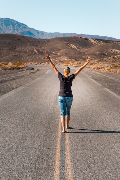 Una donna che cammina a piedi nudi su una strada deserta nella Death Valley