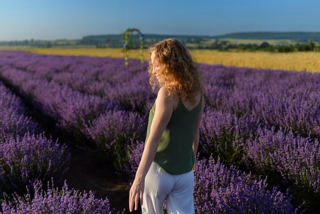 Una donna che cammina attraverso la vista posteriore del campo di lavanda