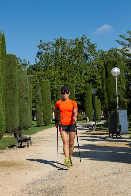 Una donna che fa nordic walking nel parco