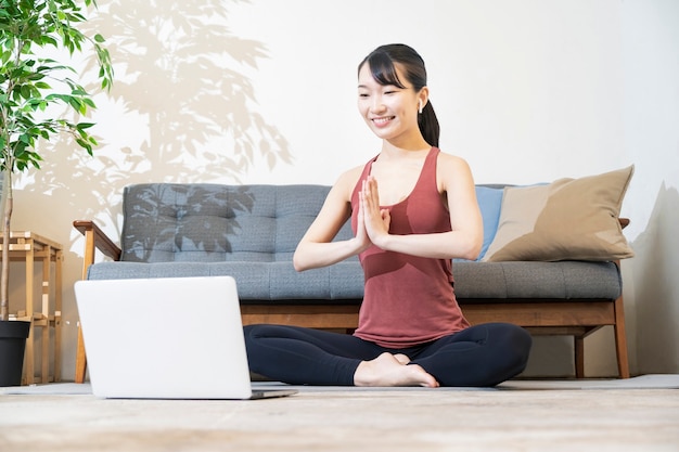 Una donna che fa yoga mentre guarda lo schermo del computer nella stanza