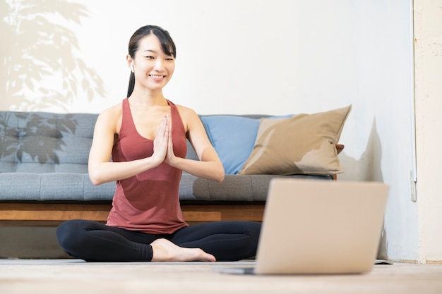 Una donna che fa yoga mentre guarda lo schermo del computer nella stanza