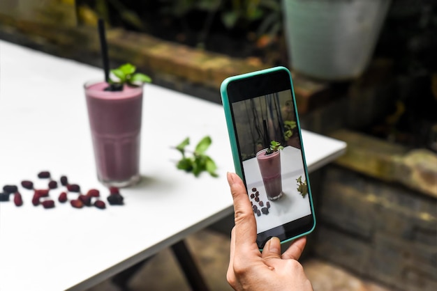 Una donna che fotografa un frullato di gelso per pubblicità e social media