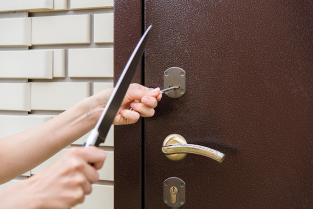 Una donna che impugna un coltello e bussa a una porta con una chiave in mano.