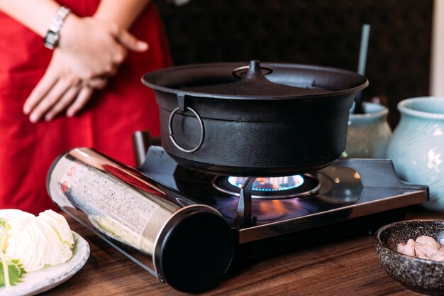 Una donna che indossa il kimono è in attesa di bollire la pentola calda di colore nero Sukiyaki.