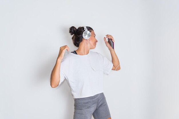 Una donna che indossa le cuffie balla davanti a un muro bianco.