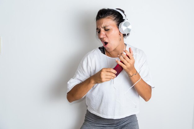 Una donna che indossa le cuffie e una maglietta bianca sta cantando e indossa una maglietta bianca.