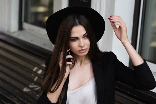 Una donna che indossa un cappello nero e usa il cellulare