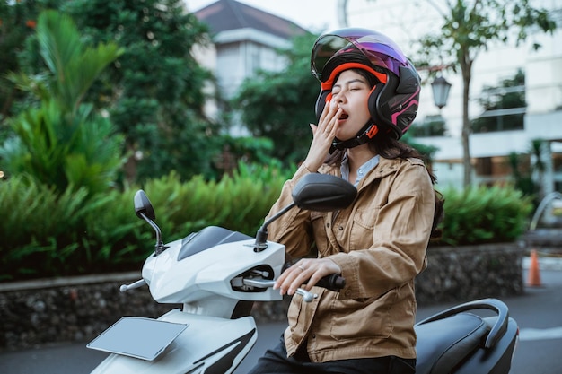 Una donna che indossa un casco smette di guidare una moto sul ciglio della strada perché ha sonno