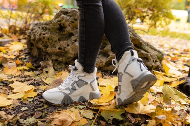 Una donna che indossa un paio di scarpe da ginnastica bianche si trova tra le foglie di un albero.