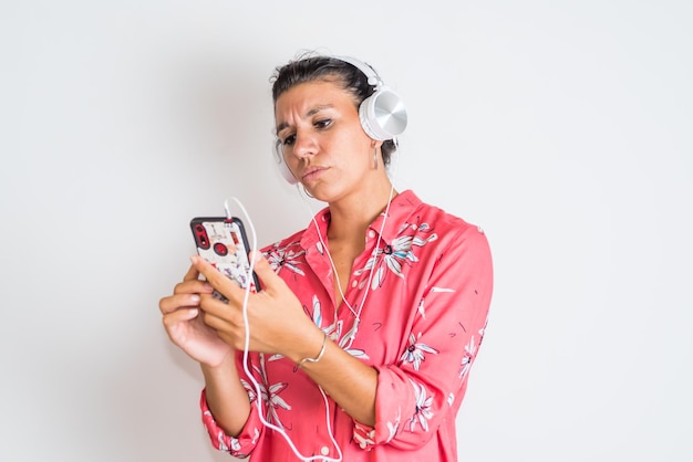 Una donna che indossa una maglietta rossa e una stampa floreale sta ascoltando musica sul suo telefono.