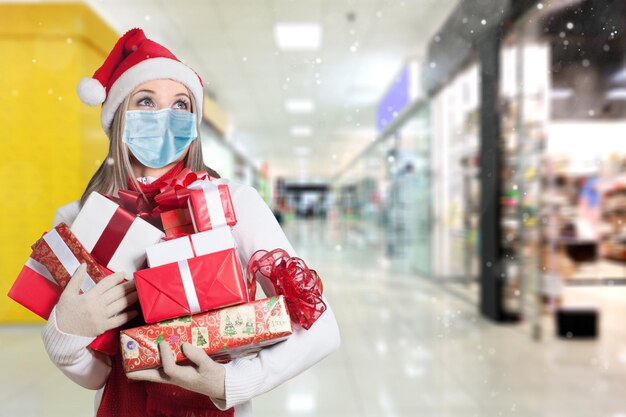 Una donna che indossa una maschera protettiva che tiene una confezione regalo nel centro commerciale
