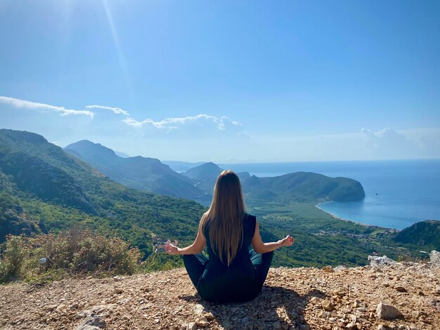 Una donna che medita su una montagna affacciata sul mare