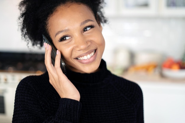 Una donna che parla al telefono sorride mostrando ai denti un ritratto ravvicinato di una dolce signora dai capelli ricci