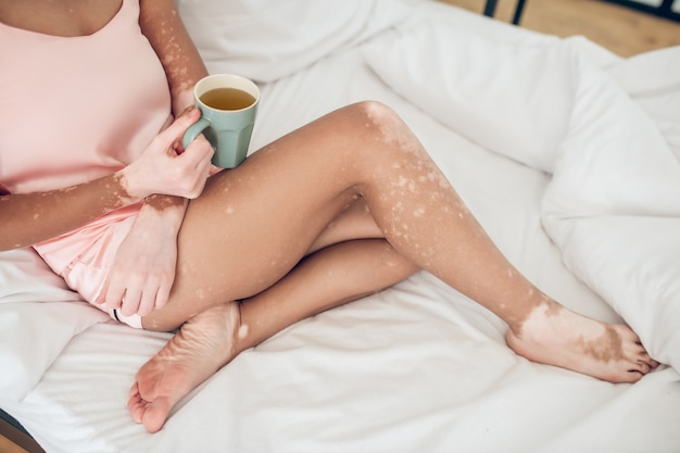 Una donna che prende il caffè al mattino mentre è a letto