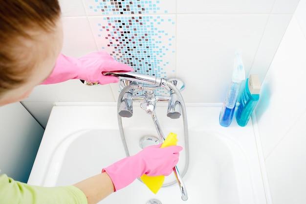 Una donna che pulisce il bagno a casa Vasca da bagno e rubinetto di lavaggio femminile