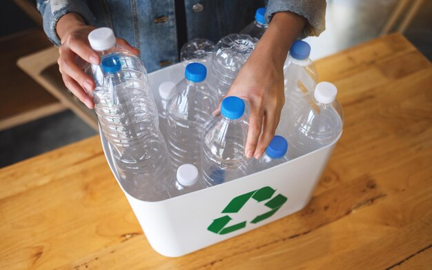 Una donna che raccoglie e separa bottiglie di plastica riciclabili in un bidone della spazzatura a casa