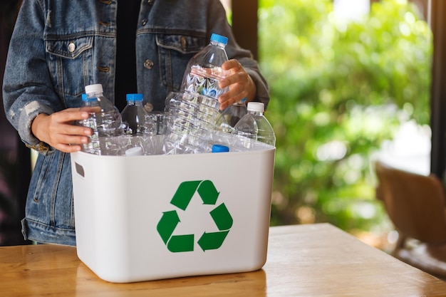 Una donna che raccoglie e separa bottiglie di plastica riciclabili in un bidone della spazzatura a casa