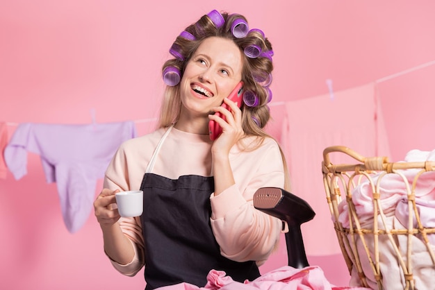 Una donna che ride ordina i servizi di pulizia della casa al telefono, stanca di fare le faccende domestiche