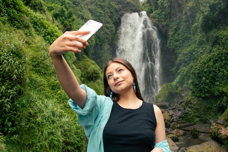 Foto una donna che scatta una foto con una cascata sullo sfondo