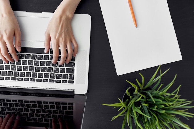 Una donna che scrive su un computer portatile con una matita accanto a lei.