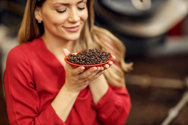 Una donna che sente l'odore dei chicchi di caffè appena tostati nella fabbrica di caffè