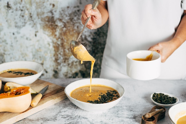 Una donna che serve zuppa di zucca all'ora di pranzo