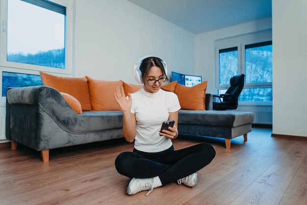 Una donna che si allena a casa con cuffie e smartphone per una videochiamata riflette lo stile di vita moderno