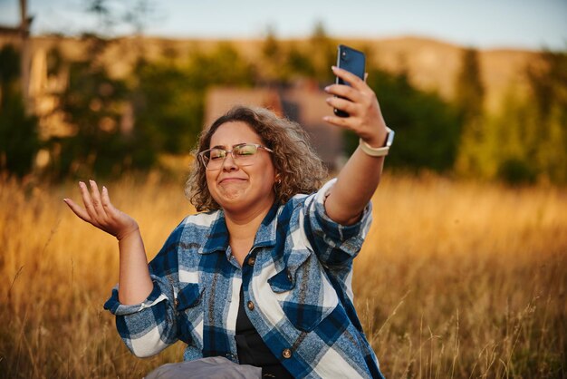 Una donna che si prende una pausa dalle escursioni nella natura che scatta foto selfie sul suo smartphone Messa a fuoco selettiva
