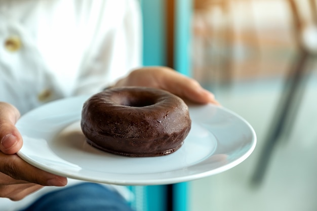 Una donna che tiene e che mostra un piatto di ciambella al cioccolato